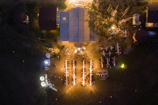 aerial view of outdoor event with dining tables arranged in rows illuminated by lights and surrounded by trees showcasing a gathering of guests enjoying dinner festivities 4 festive gatherings party atmosphere